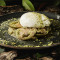 Burrata Inyectada De Pesto Sobre Tartar De Berenjena Asada, Tomate Kumato Y Tierra De Pistacho